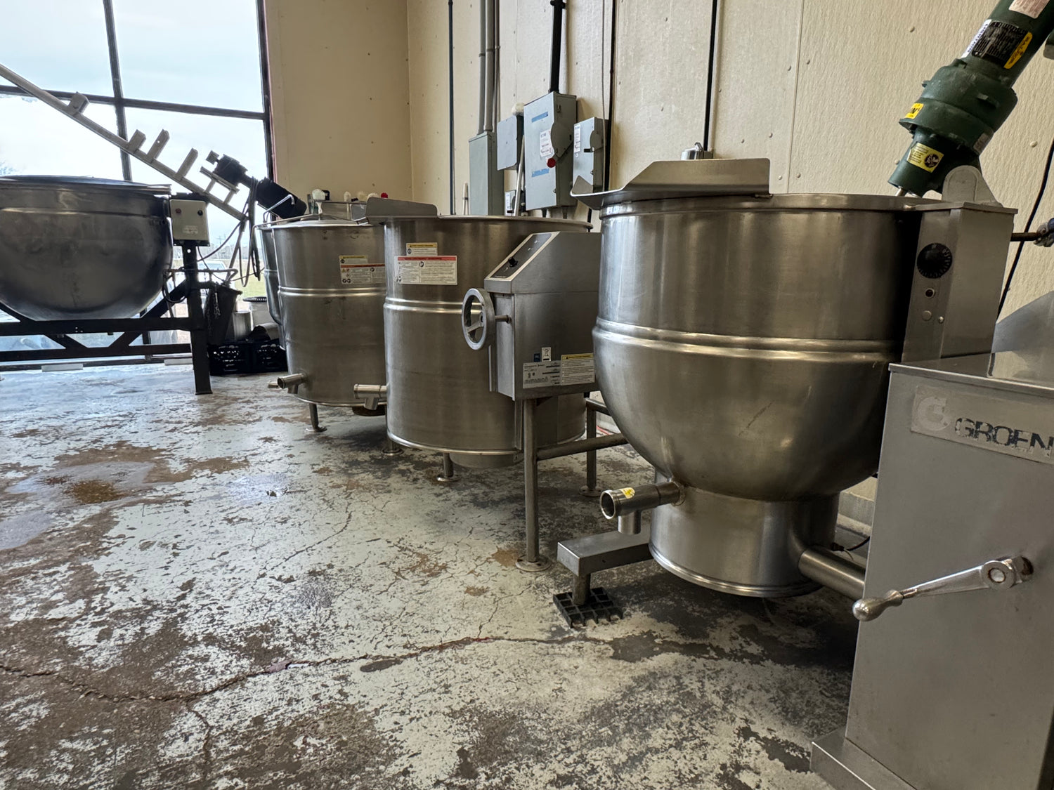 Row of industrial stainless steel mixers in a warehouse setting